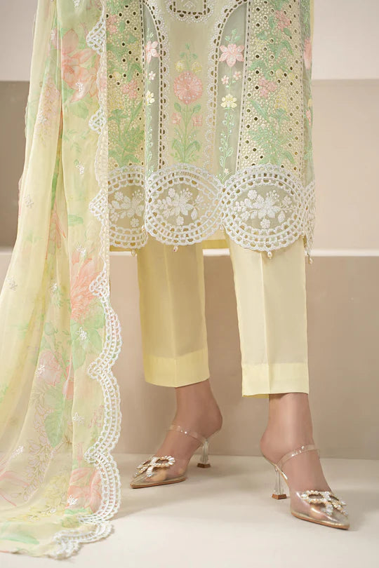 Woman wearing a light green embroidered top and yellow pants with white lace details.