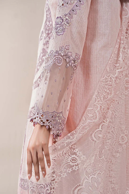 Close-up of a hand wearing a pink embroidered dress with intricate patterns.