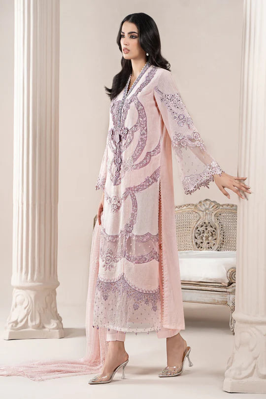 Woman wearing a pink and white embroidered traditional outfit in a decorative setting.