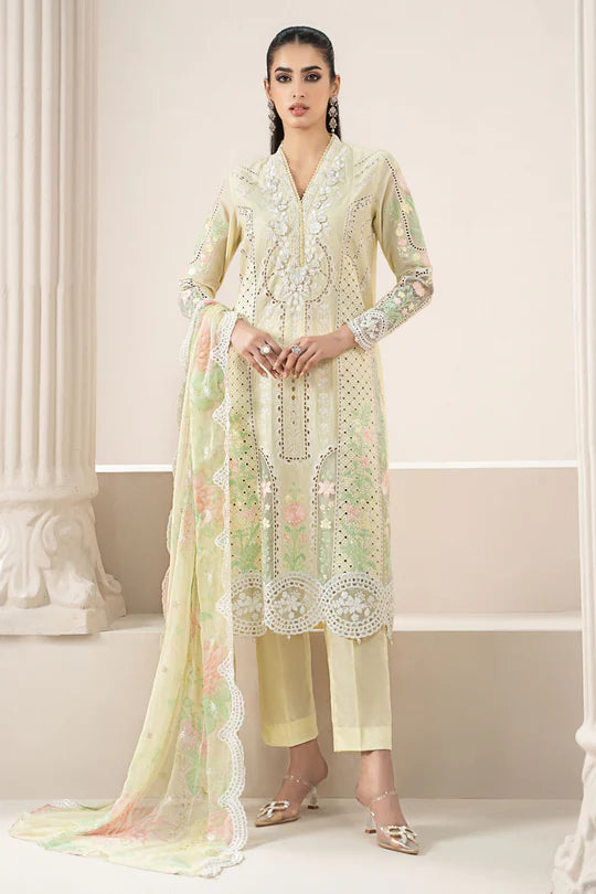 Woman wearing a light green embroidered outfit with a sheer dupatta in a decorative setting.