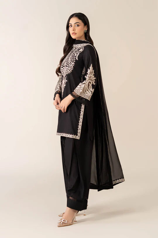 Woman wearing a black outfit with white embroidery on a beige background