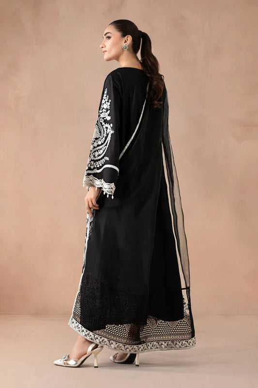 Woman wearing a black traditional outfit with white embroidery against a beige background