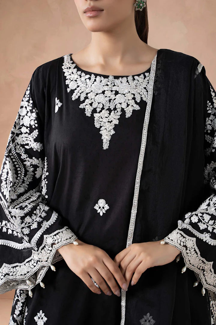 Black outfit with white embroidery on a beige background