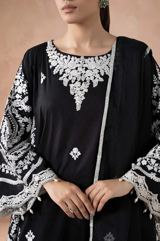 Black outfit with white embroidery on a beige background