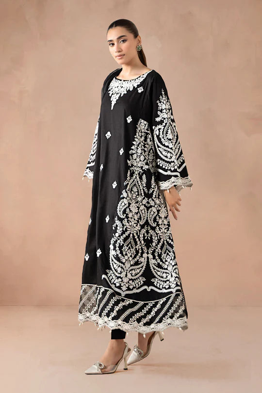 Woman wearing a black and white embroidered outfit against a beige background