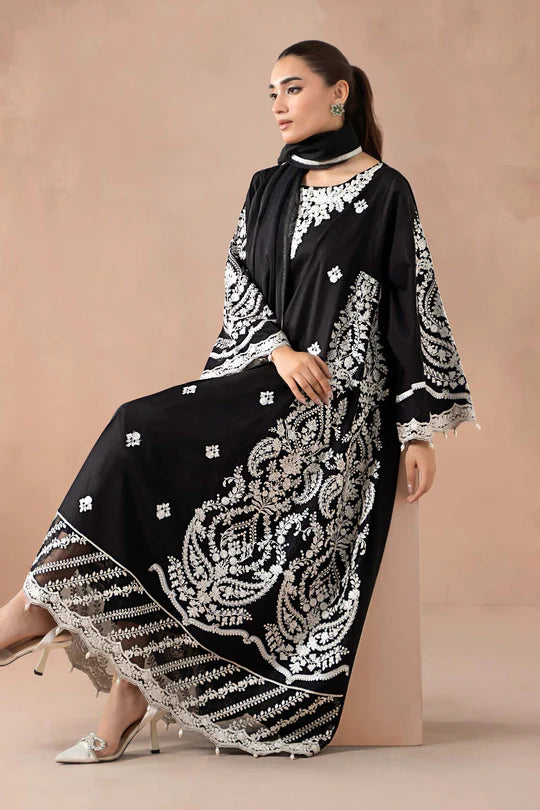 Woman wearing a black and white embroidered abaya against a beige background