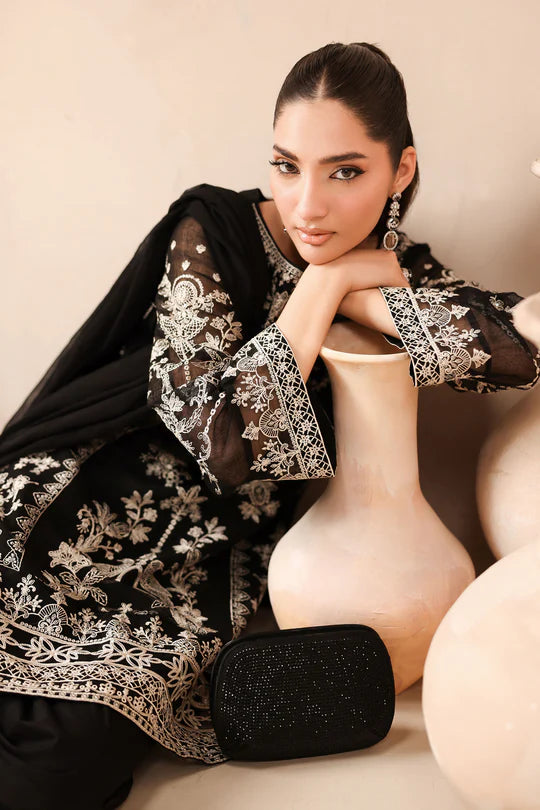 Woman wearing a black and white embroidered outfit with a beige background