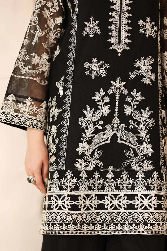 Black fabric with intricate white embroidery on a beige background