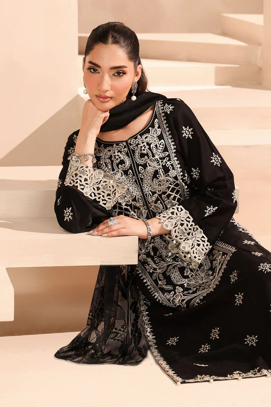 Woman in black and white embroidered traditional outfit sitting on a staircase.