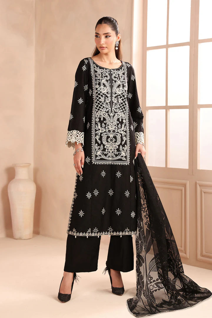 Woman wearing a black embroidered outfit with a sheer dupatta in a well-lit room.