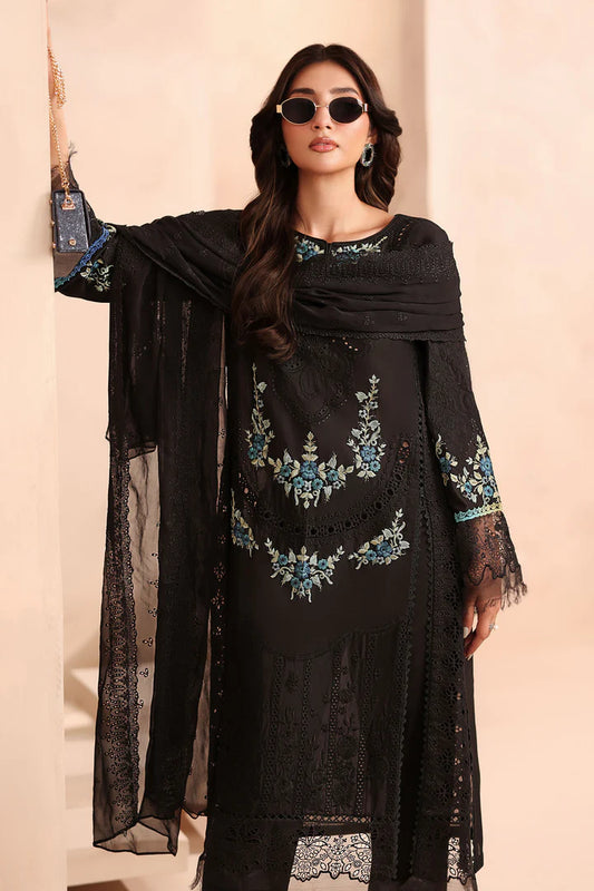 Woman wearing a black embroidered dress with sheer sleeves against a beige background
