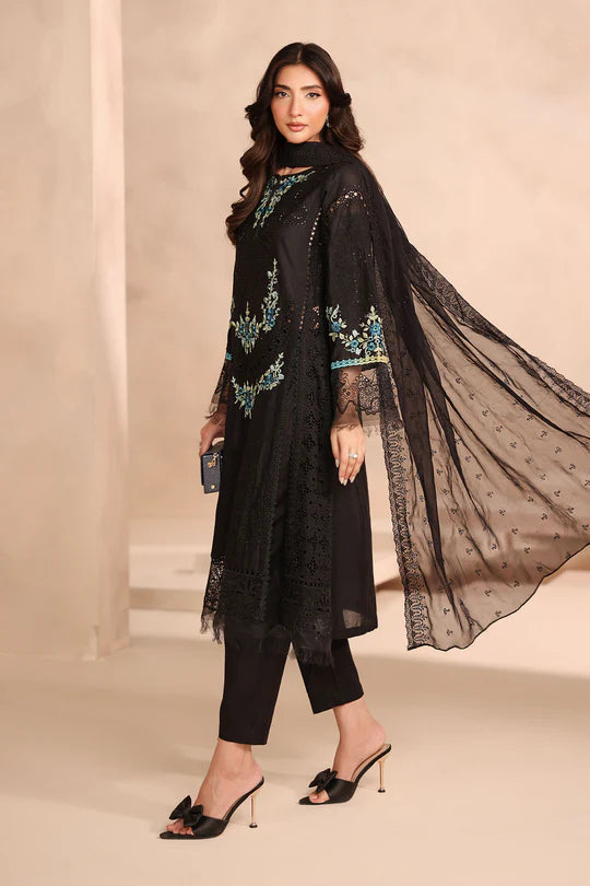 Woman wearing a black embroidered outfit with a sheer dupatta on a beige background