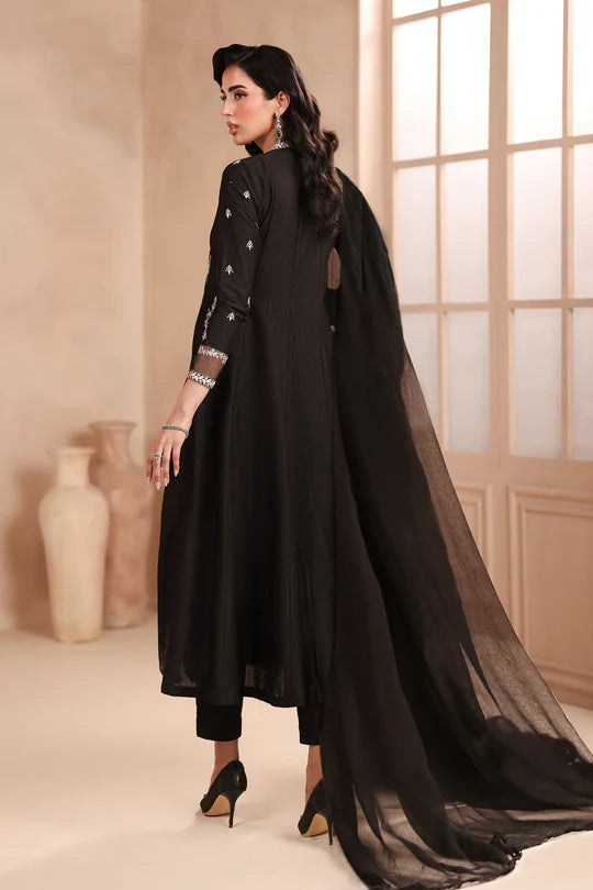 Woman wearing a black traditional outfit with a long scarf in a well-lit room.