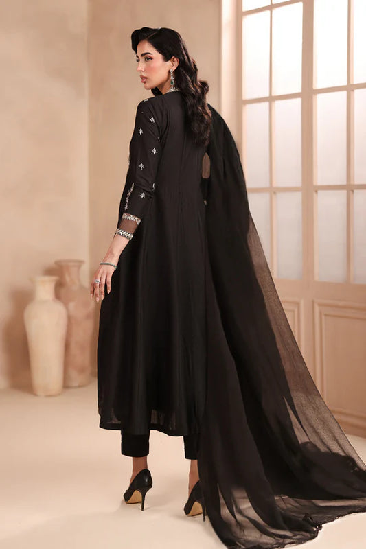 Woman wearing a black traditional outfit with a long scarf in a well-lit room.