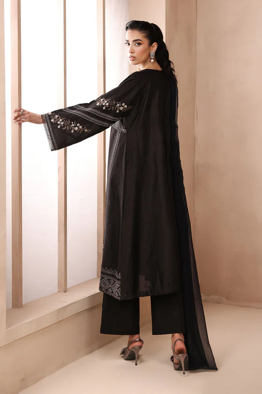 Woman wearing a black outfit with floral embroidery in a minimalistic setting