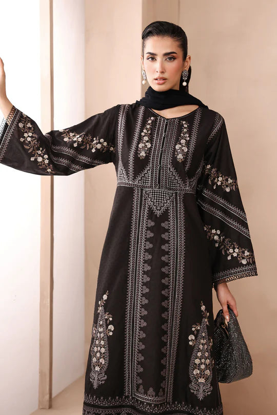Woman wearing a black embroidered dress with a plain background