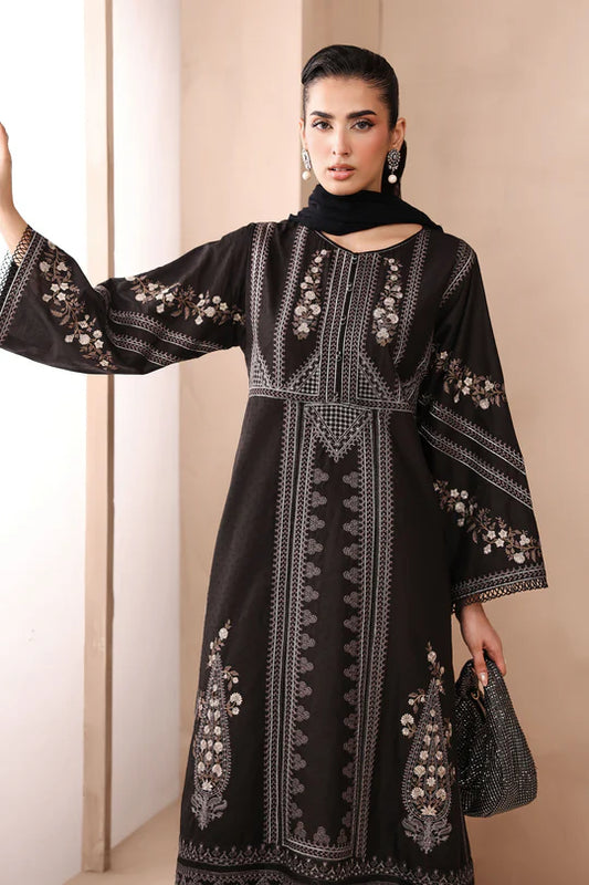 Woman wearing a black embroidered dress with a plain background