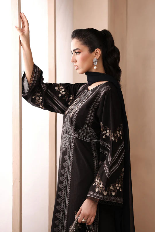 Woman wearing a black embroidered abaya against a beige background