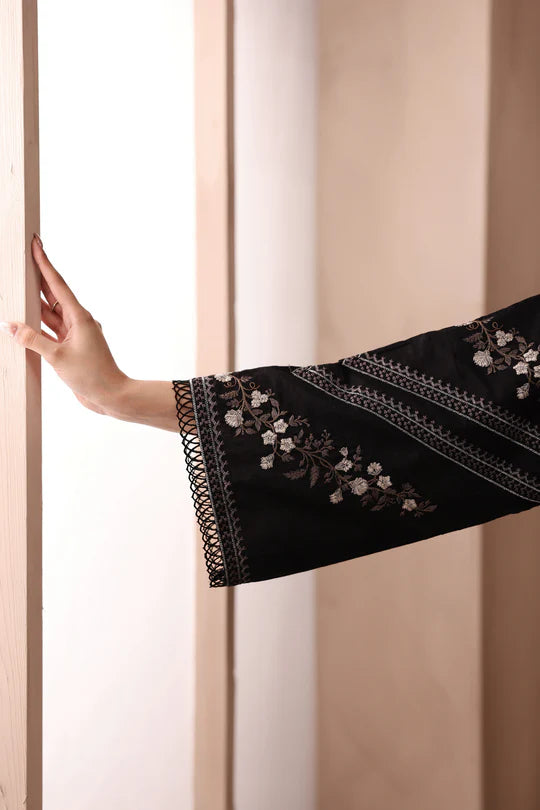 Black sleeve with floral embroidery held against a neutral background
