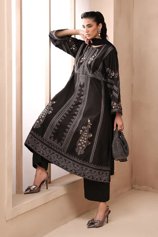 Woman wearing a black embroidered outfit with a neutral background