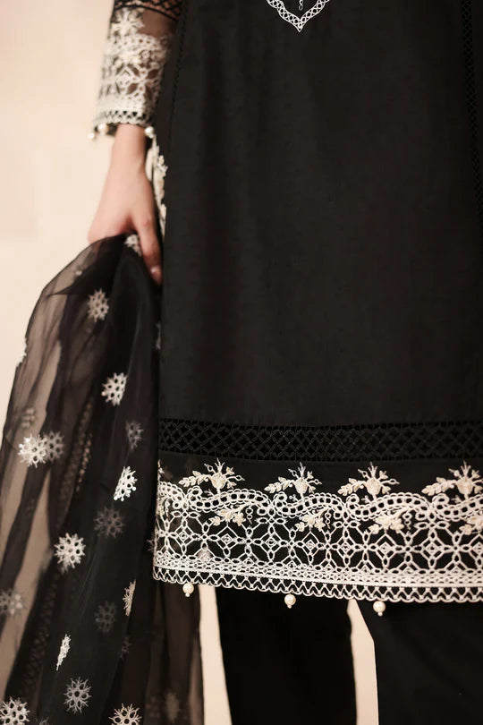 Black outfit with white embroidery details on a beige background