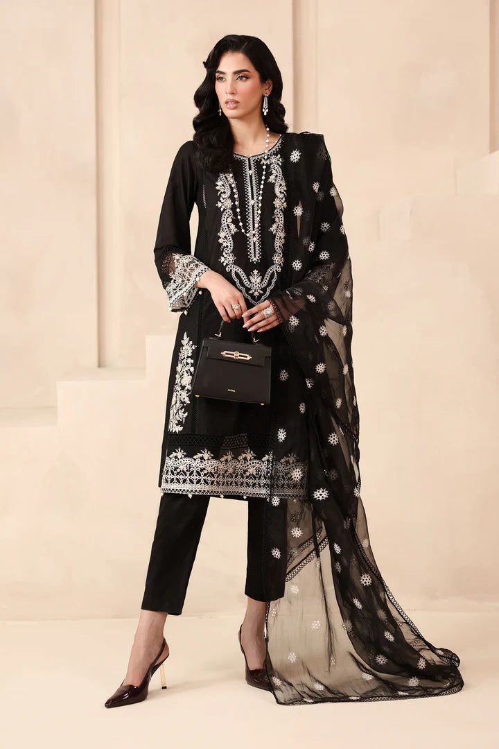Woman wearing a black embroidered outfit with a sheer dupatta against a beige background