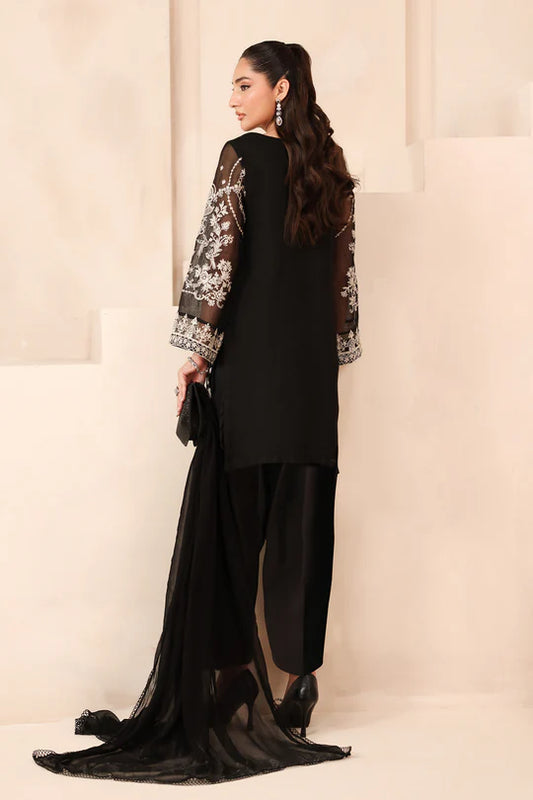 Woman in a black outfit with floral sleeves against a beige wall