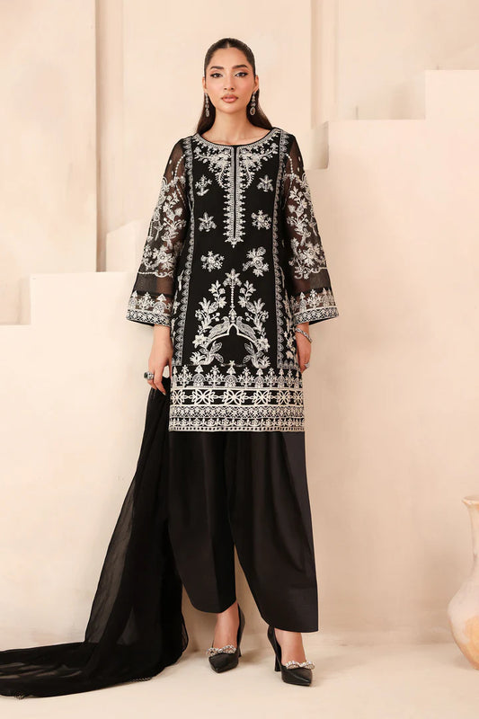 Woman wearing a black and white embroidered traditional outfit with black pants on a beige background