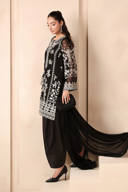 Woman wearing a black and white embroidered outfit with a flowing drape against a beige background
