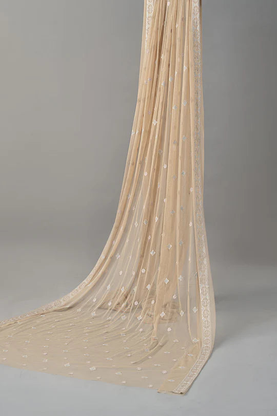 Beige sheer fabric with small embellishments on a gray background