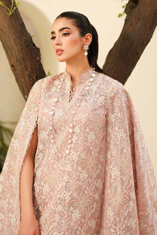 Woman wearing a light pink embroidered traditional outfit with a tree in the background
