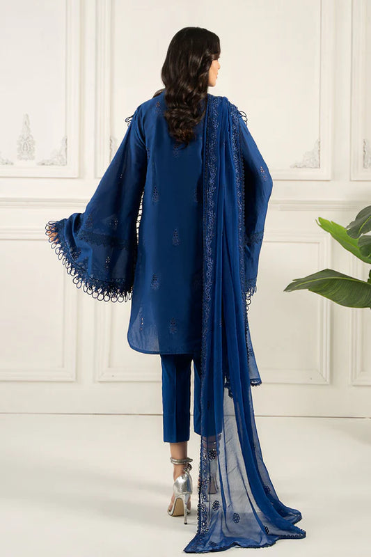 Woman wearing a blue traditional outfit with a matching dupatta against a white wall.