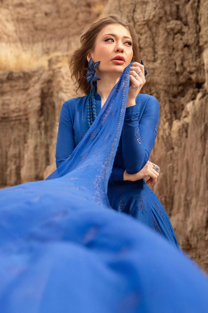 Woman in a blue dress holding a blue scarf against a rocky background