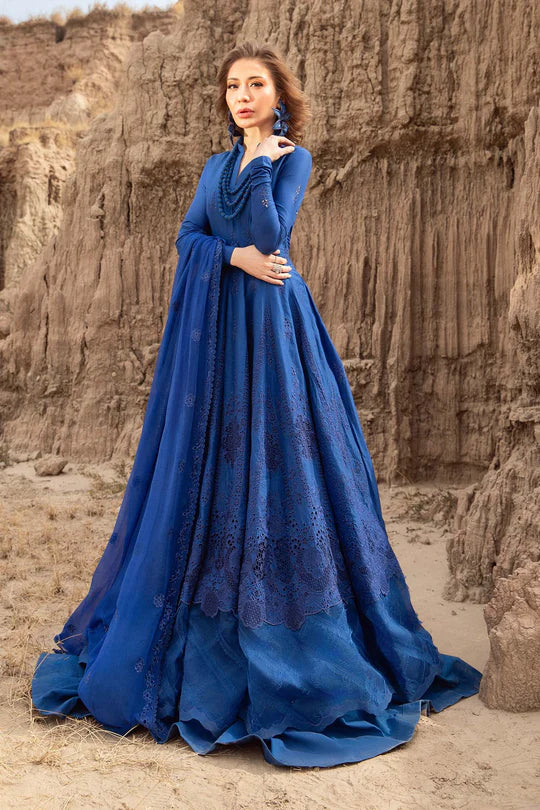 Woman in a blue dress standing in front of rocky cliffs.