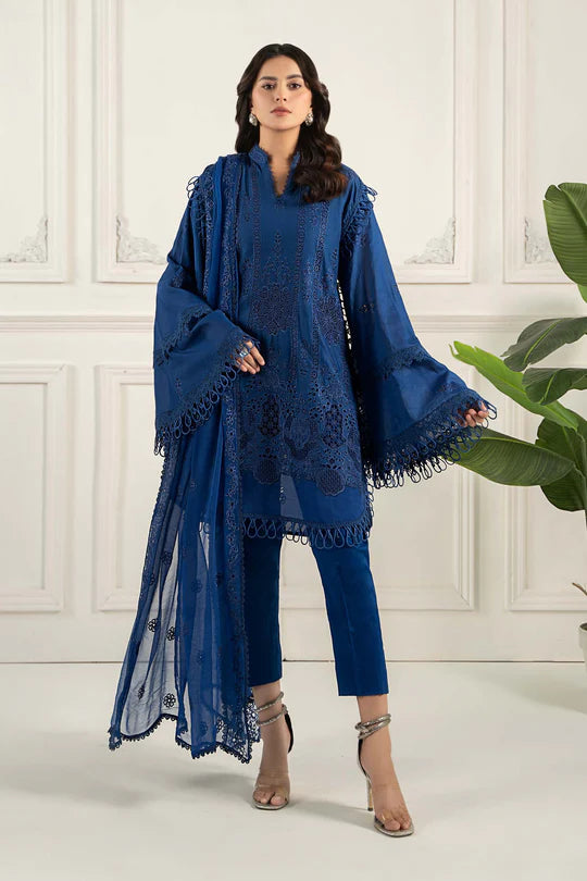 Woman wearing a blue lace outfit with a white wall and plant in the background