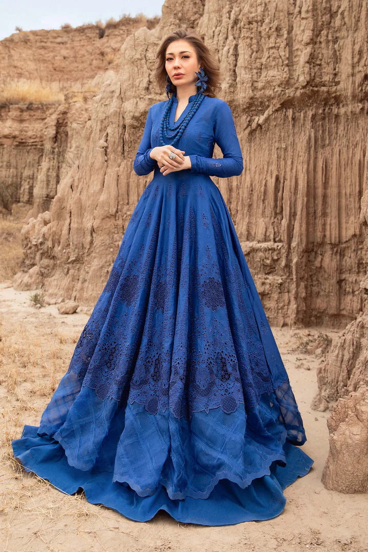 Woman in a blue dress standing in front of rocky cliffs