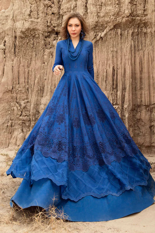 Woman wearing a blue lace dress standing against a textured stone wall.