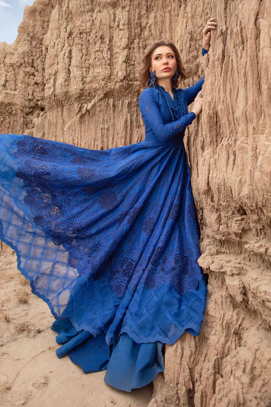 Woman in a blue dress standing against a rocky wall