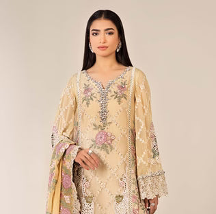 Woman wearing a beige embroidered traditional outfit with floral patterns on a plain background
