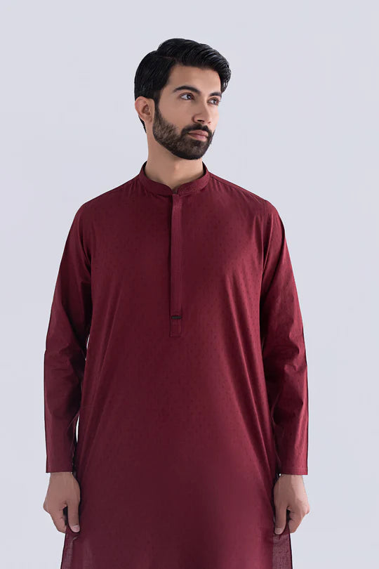 Man wearing a maroon traditional outfit on a white background