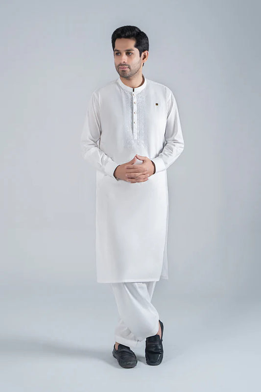 Man wearing a white kurta with black shoes on a light gray background