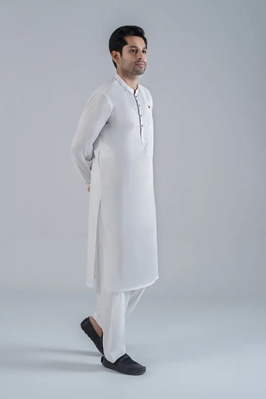 Man wearing a white kurta with black shoes on a light gray background