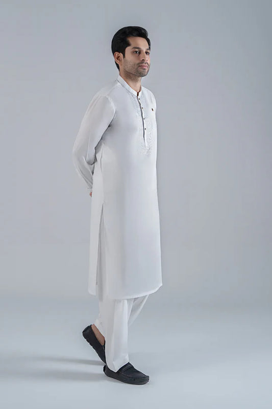 Man wearing a white kurta with black shoes on a light gray background