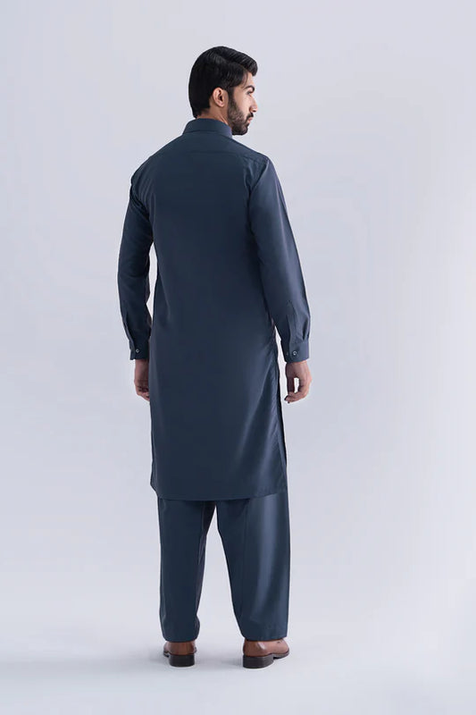 Man wearing a dark blue traditional outfit on a light gray background