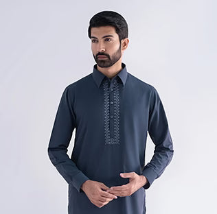 Man wearing a dark blue embroidered shirt against a white background