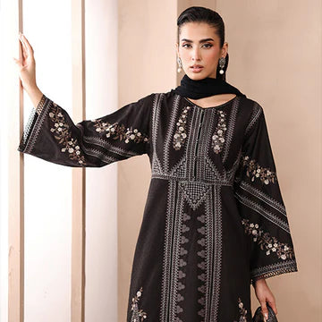 Woman wearing a black embroidered dress against a beige background