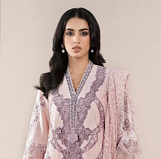 Woman wearing a pink and white embroidered traditional outfit against a beige background