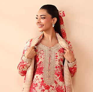 Woman wearing a red and white floral traditional outfit with a matching dupatta against a beige background